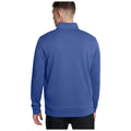A person is standing with their back facing the viewer, wearing a blue pullover sweatshirt in a neutral background setting, suggesting a casual and relaxed environment.