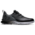 A black athletic shoe with a textured surface and a gray outsole sits on a flat surface showcasing its sleek design and lacing system meant for comfort and performance.