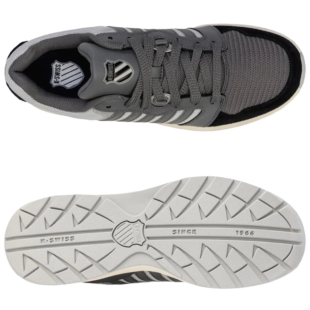 A grey athletic shoe with a textured mesh upper is positioned above its white rubber sole featuring a patterned tread displaying the brand name K-Swiss and the year 1966.
