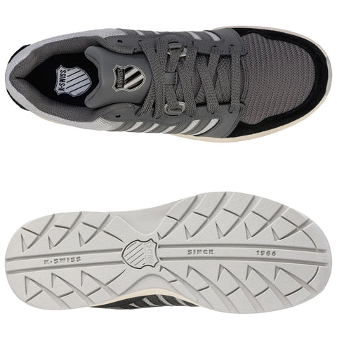 A grey athletic shoe with a textured mesh upper is positioned above its white rubber sole featuring a patterned tread displaying the brand name K-Swiss and the year 1966.