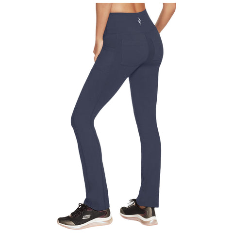 Navy blue leggings are worn by a person standing with their back to the viewer showcasing sleek design and pockets in a casual environment with athletic shoes.