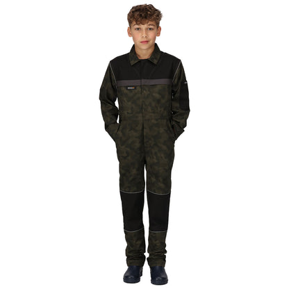 A child stands upright wearing a camouflage-patterned jumpsuit with black accents and pockets while looking directly at the viewer in a plain white background environment.