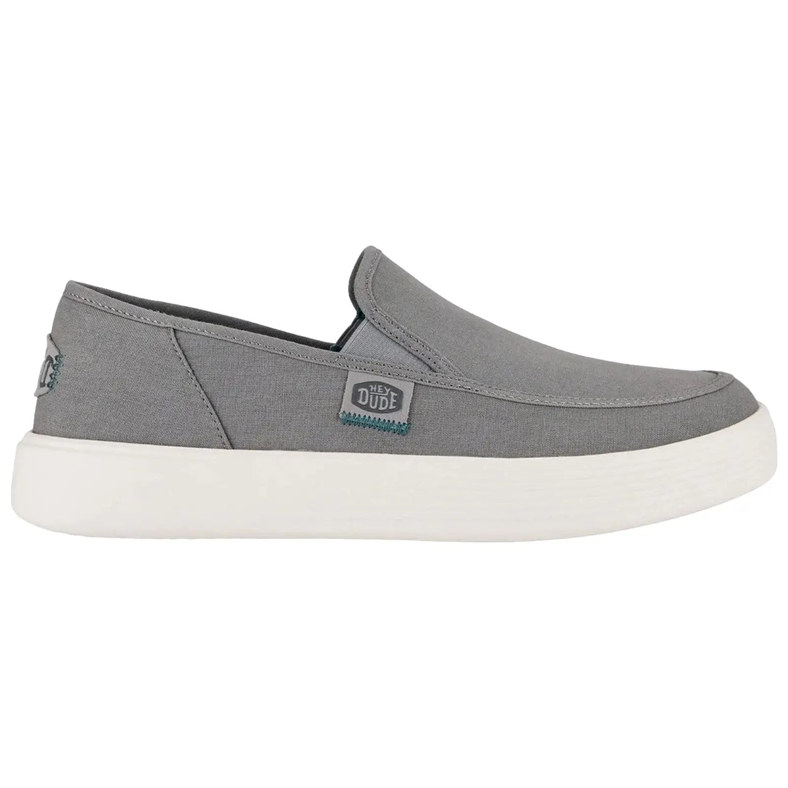 A gray slip-on shoe features a low profile and a white rubber sole with a textured pattern ideal for casual wear and comfort in various settings.