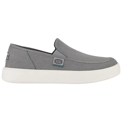 A gray slip-on shoe features a low profile and a white rubber sole with a textured pattern ideal for casual wear and comfort in various settings.