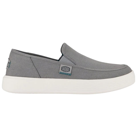 A gray slip-on shoe features a low profile and a white rubber sole with a textured pattern ideal for casual wear and comfort in various settings.