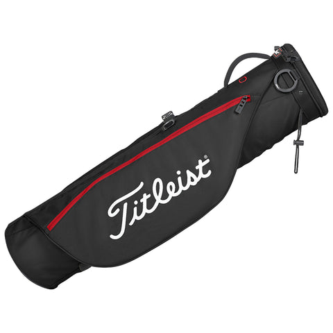 A black golf bag with red accents sits upright featuring the Titleist logo prominently displayed on the side it is designed to hold golf clubs and accessories in a compact manner