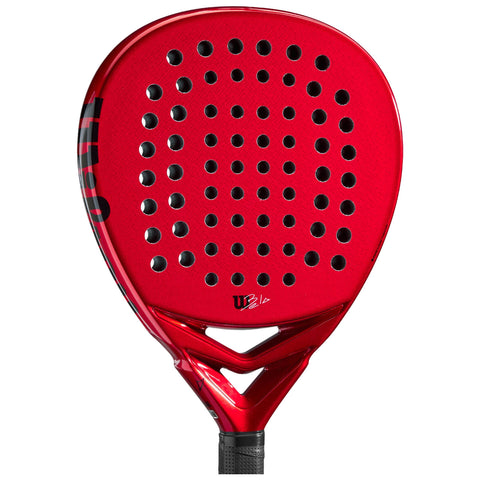 A bright red padel racket with a perforated surface and a triangular frame is displayed against a neutral background highlighting its sleek design and grip texture.