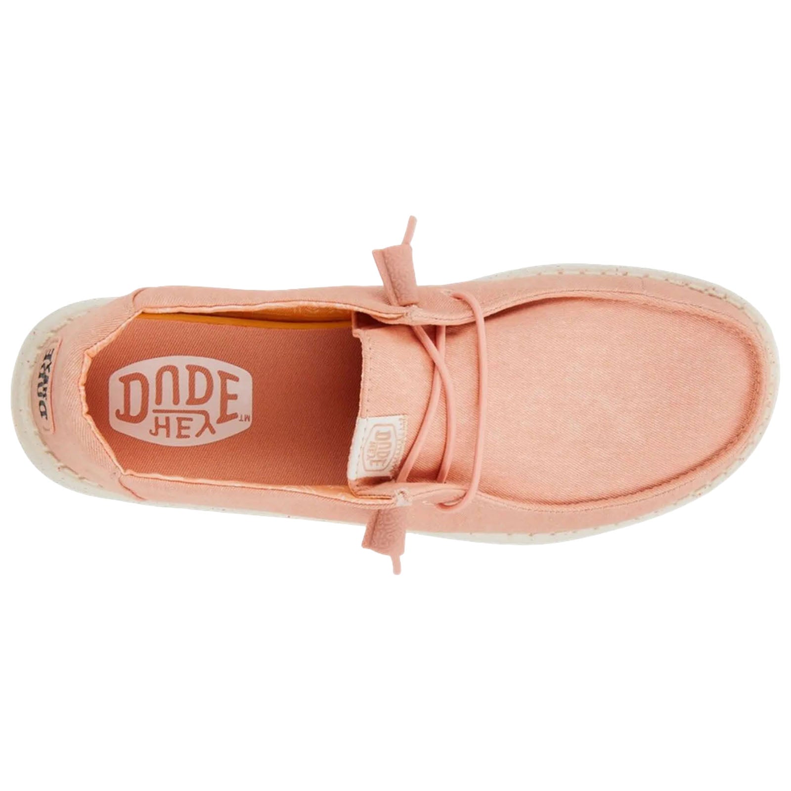 A pink slip-on shoe with a textured surface sits against a plain background showcasing its soft fabric and decorative laces emphasizing casual style and comfort. The interior features a logo.