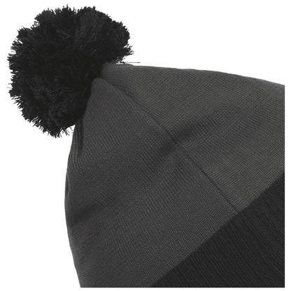 A black knitted beanie with a pom-pom on top is positioned at an angle, showcasing its textured fabric and snug fit, suitable for cold weather wear.