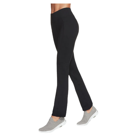 Black pants are being worn by a person walking in gray slip-on shoes in a neutral background, emphasizing the sleek look and comfortable style of the outfit.