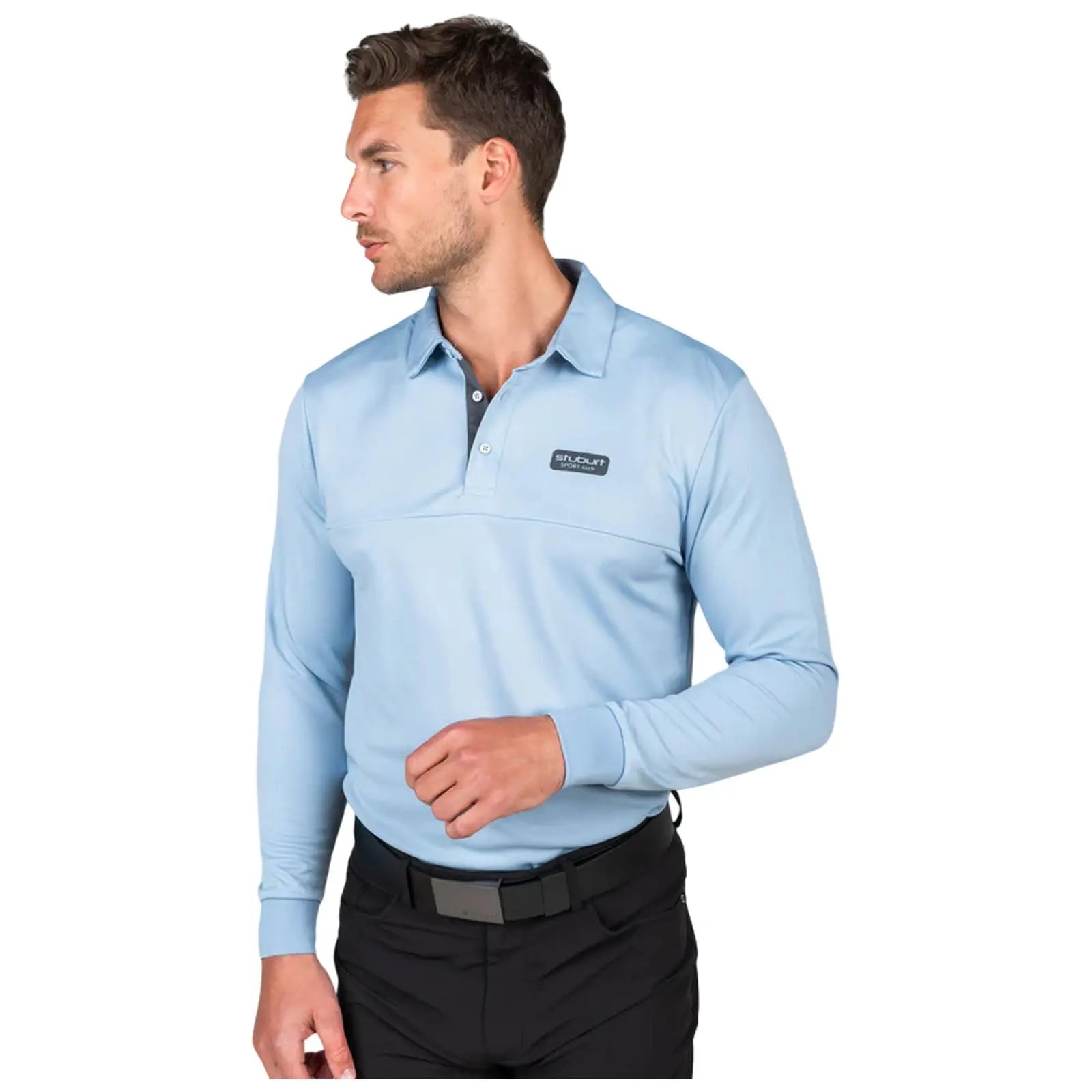 A man wearing a light blue long-sleeve polo shirt and black pants stands in profile with one hand raised as if gesturing in a neutral setting.