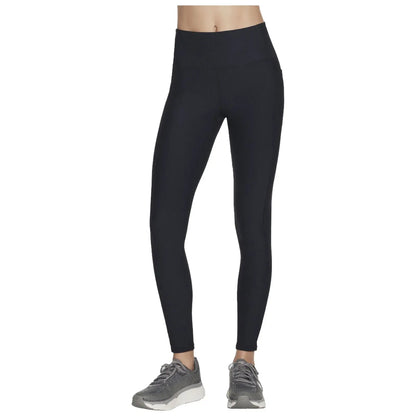 A pair of black leggings are displayed standing upright showcasing a ribbed texture with a high waistband alongside gray athletic shoes suggesting an active lifestyle.