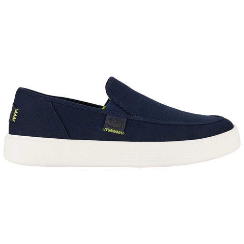 A navy blue slip-on shoe with a white sole is displayed horizontally the shoe features a small logo and contrasting stitching providing a casual appearance suitable for relaxed environments