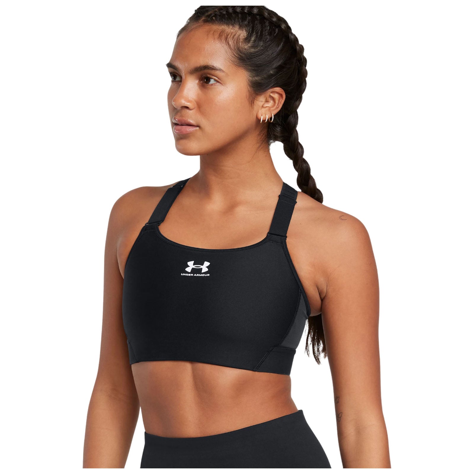 A woman with braided hair is wearing a black athletic sports bra and looking confidently to the side in a neutral background, suggesting a fitness or athletic context.
