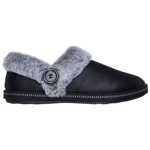 A black slipper with a grey fur collar and a decorative button is positioned sideways showcasing its soft exterior and textured sole in a simple, uncluttered background.