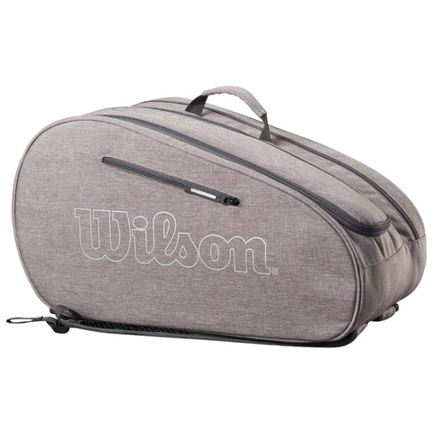 A gray tennis bag is positioned on a flat surface featuring a zipper and a handle its side displays the word Wilson in bold white letters designed for carrying tennis equipment.