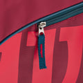 A vibrant red bag with a blue zipper is partially open showcasing a zipper pull. The context suggests it is likely used for carrying items or sports equipment.