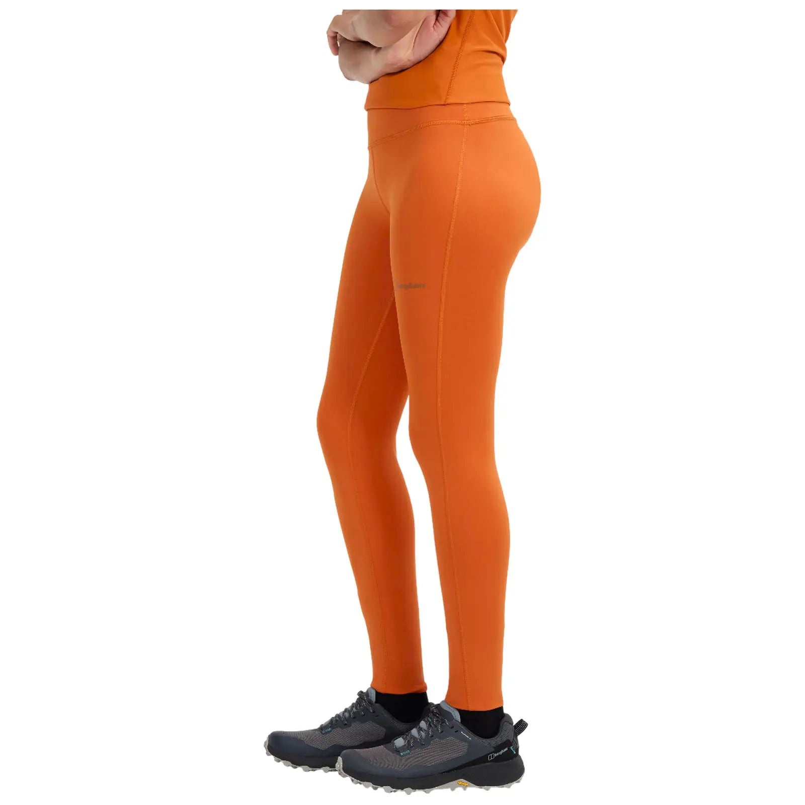 A person wearing a cropped white top and black leggings is walking away, showcasing their outfit with a focus on the sleek design of the leggings and athletic shoes.