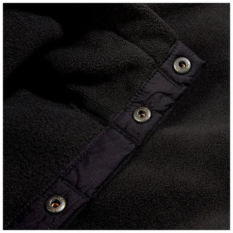 A close-up of a black fleece fabric featuring a button closure with metallic snaps the material appears soft and has a textured surface against a dark background.