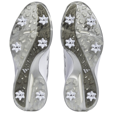 Two athletic shoes viewed from the bottom show a patterned gray outsole with six white cleats each designed for traction on grass or turf fields.