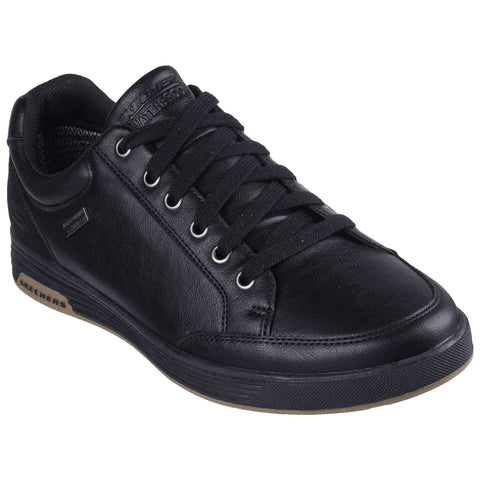 A black sneaker features a smooth leather upper with rounded toe and flat sole laced securely in place displayed against a neutral background designed for casual wear and comfort