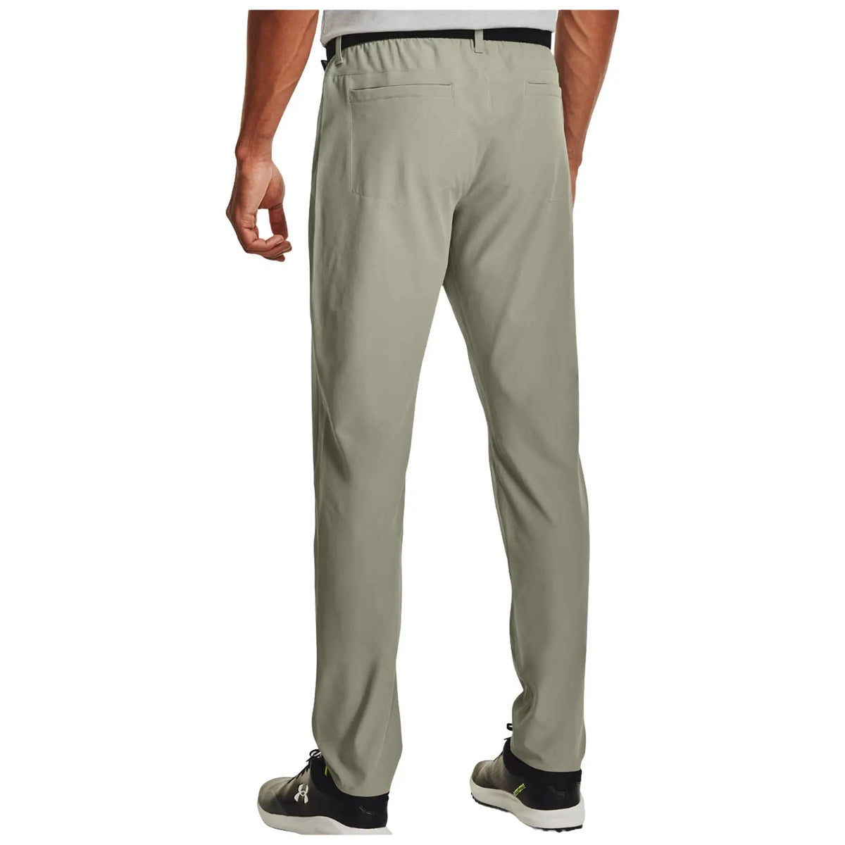A person stands with their back towards the viewer wearing light green pants with a relaxed fit and two back pockets while wearing black and gray shoes in a neutral background.