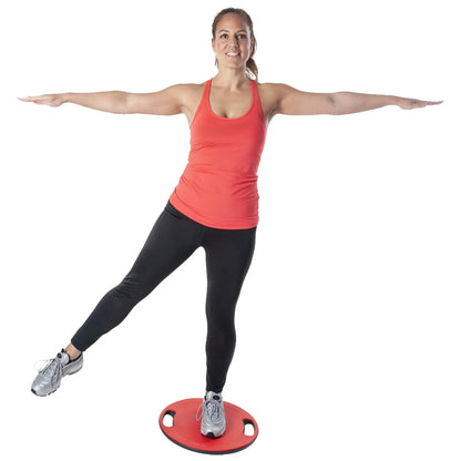 A woman in a red tank top and black leggings stands on a balance board with one leg raised and arms extended for balance in a neutral background.