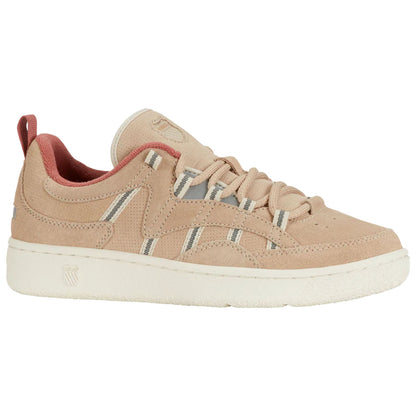 A tan suede sneaker features thin white and grey stripes and a red inner lining with traditional laces while resting on a flat surface in a neutral environment.