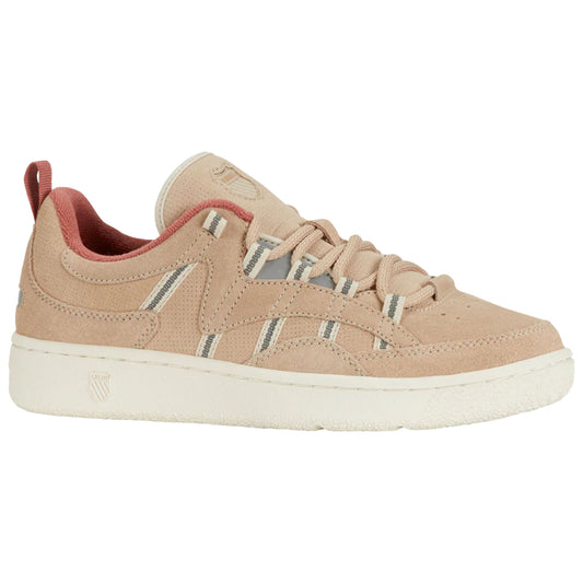 A tan suede sneaker features thin white and grey stripes and a red inner lining with traditional laces while resting on a flat surface in a neutral environment.