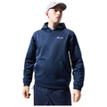 A young person wearing a navy hoodie and matching pants stands confidently with one hand on their hip and gazes slightly upward against a white background.