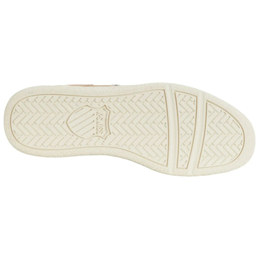 A sneaker sole rests flat on a surface displaying a textured rubber pattern designed for grip and traction with a circular logo at the center and an overall light color scheme.