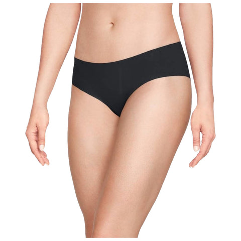 A woman is wearing black underwear while standing. Her left hand rests against her hip and her right hand is slightly raised near her side. The background is plain and light-colored.