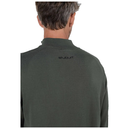 A person with short hair is wearing a dark green sweater featuring a small black logo on the back. The environment appears neutral and unobtrusive.