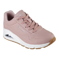 A pink sneaker with a smooth surface features lace-up design and a cushioned heel. It shows branding on the side and has a white sole with a textured gum rubber bottom.