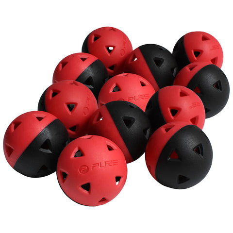 A cluster of rubber balls features a mix of red and black halves with triangular cutouts scattered together on a flat surface, suggesting play or sport-related activity.