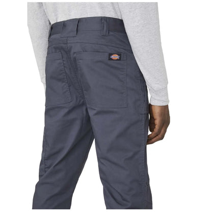 A person stands wearing gray long sleeves and dark gray pants with two back pockets showcasing a label on the waistband the setting is neutral and focused on the clothing details.
