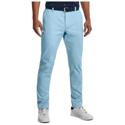 Light blue golf chinos are worn by a person standing still. The outfit is complemented by a dark shirt and white shoes, perfect for a casual outdoor appearance on a sunny golf day.