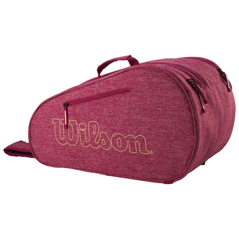 A maroon tennis bag is displayed with a prominent Wilson logo. It features multiple zippered compartments and a carrying handle, designed for storing and transporting tennis equipment.