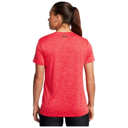 A person with long hair tied back wears a red athletic t-shirt, facing away. The setting is neutral, highlighting the clothing without other distractions.