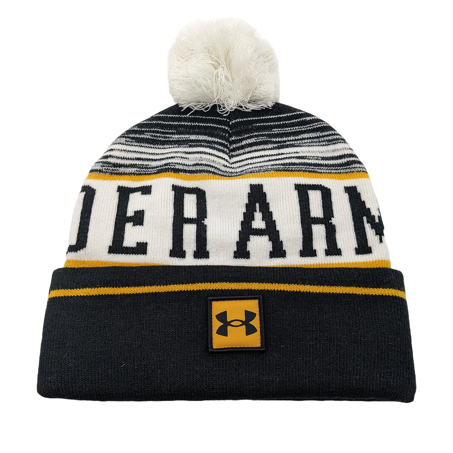 A knitted beanie with a white and black striped pattern features bold yellow and black letters spelling "UNDER ARMOUR" on the body and a logo patch sewn on the front. A fluffy pom-pom sits atop the hat.