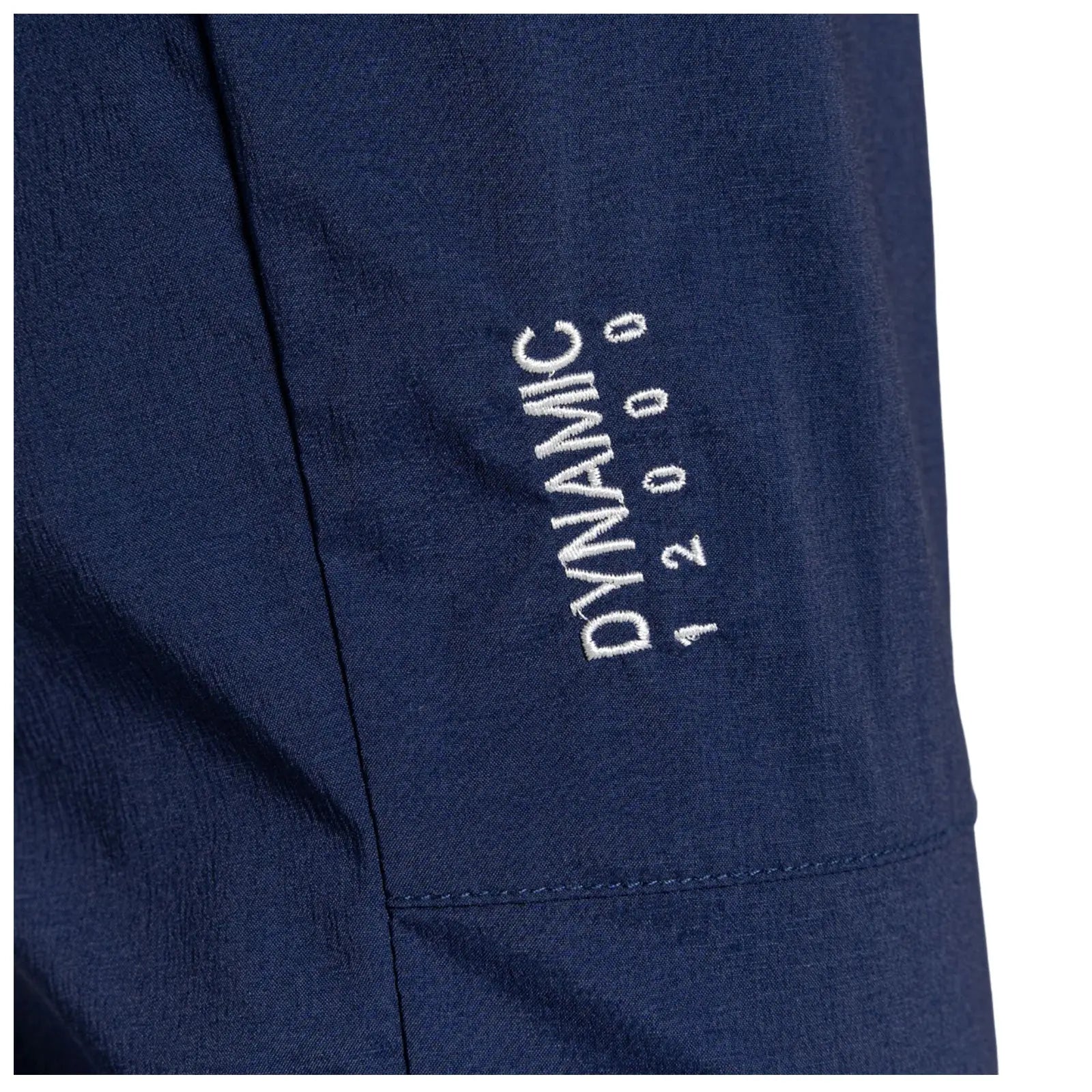 A close-up of a dark blue fabric featuring white embroidered text that reads DYNAMIC 12000 positioned on the side seam indicating a garment's branding and characteristics.