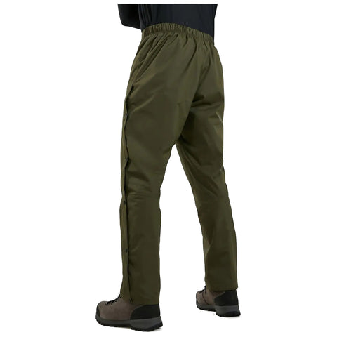 Olive green pants with an elastic waistband and side snaps are worn by a person standing. The individual is dressed in outdoor footwear, preparing for an outdoor activity.
