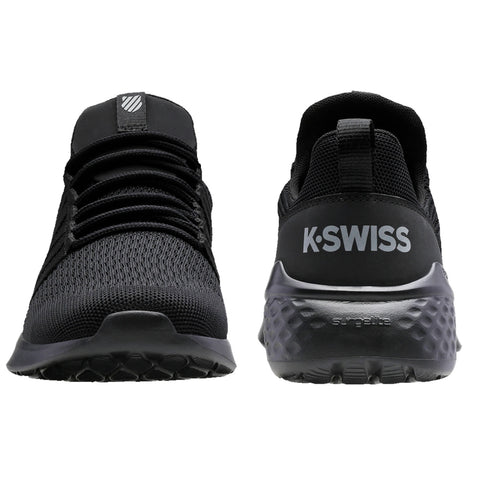 Black athletic shoes are displayed upright showcasing a mesh upper and rubber sole with a textured pattern K-Swiss branding is visible on the heel in contrasting white.