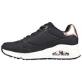 A black sneaker with a white sole features a cushioned air unit in the heel and metallic accents at the back with laces threaded through eyelets on the upper.