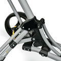 A stroller frame is positioned prominently on a white background featuring gray metal tubes with black joints and yellow elements highlighting the wheel area and connection points for functionality.