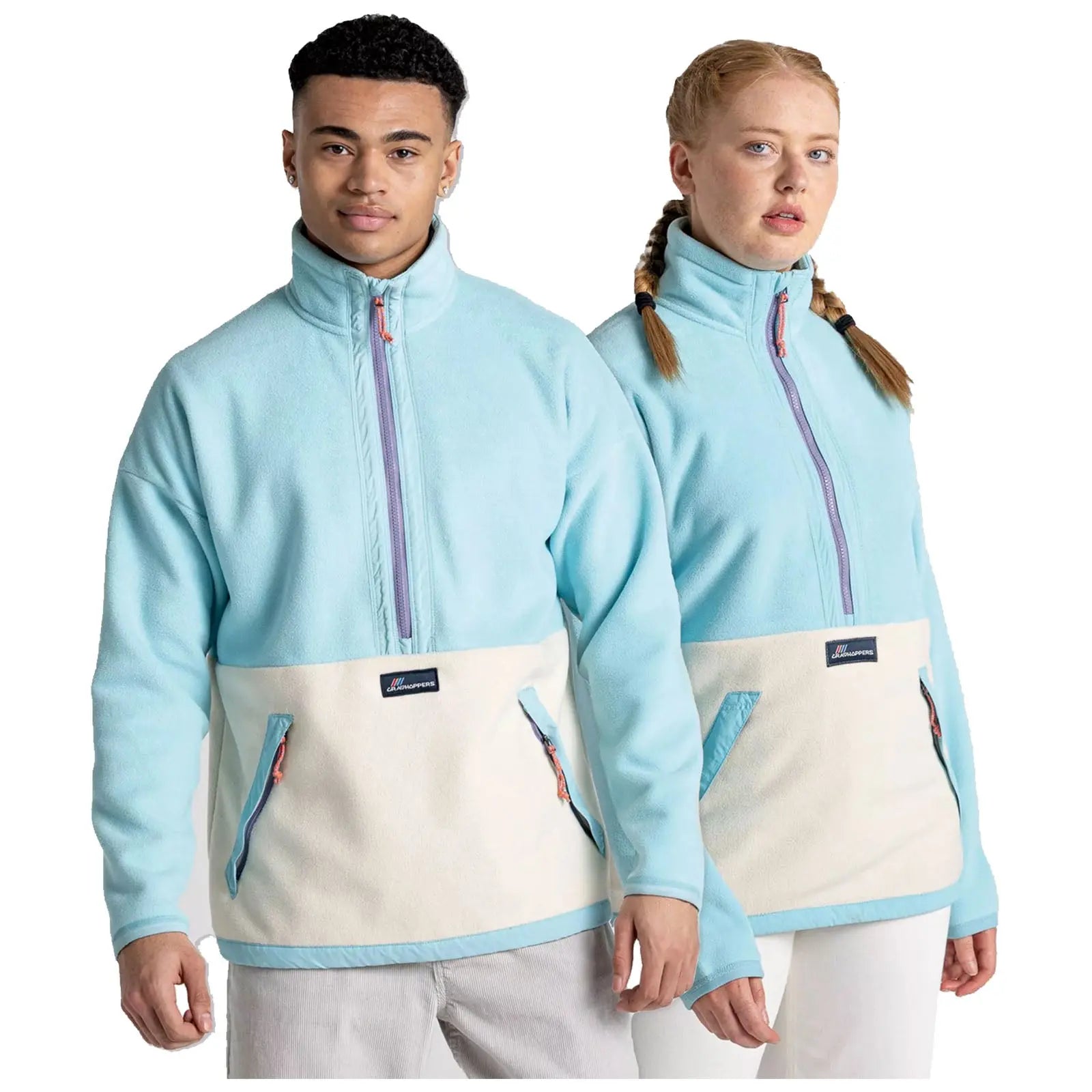 Two young adults stand side by side, both wearing matching blue and white fleeced jackets with half-zippers and large pockets, posing against a plain white background.
