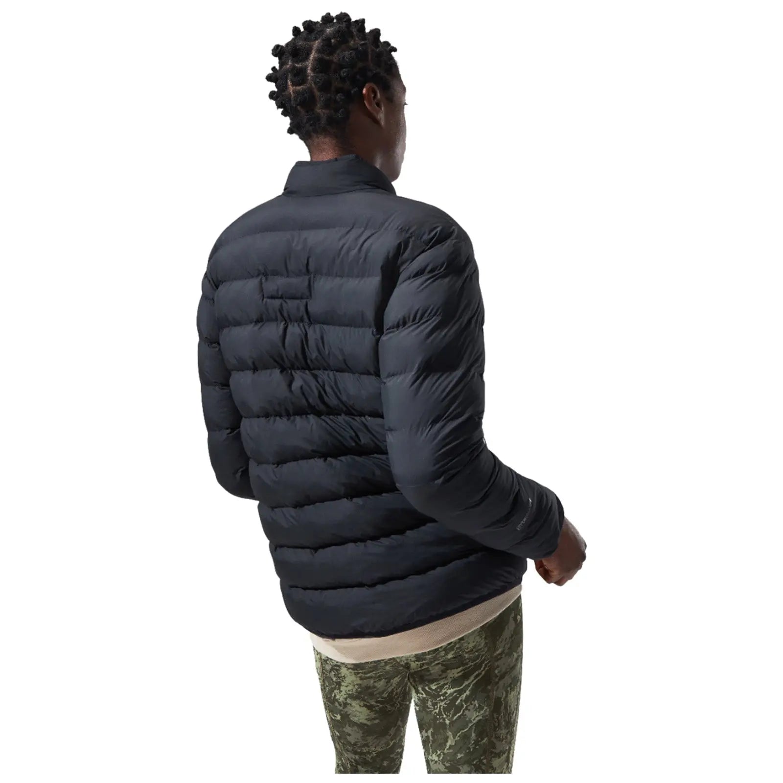 A person wearing a black puffer jacket and camo pants stands with their back turned, appearing to look away in a minimalist setting with a white background.