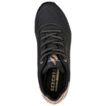 A black sneaker with perforated details and brown laces rests upright showcasing the Skechers logo and memory foam insole amidst a neutral background.