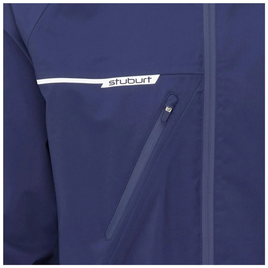 A navy blue jacket features a white logo on the chest with a zippered pocket visible on the front side, placed in a neutral indoor setting.