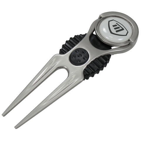 A golf tee marker is positioned upright with two prongs at the bottom and a circular button on top featuring a logo, set against a plain background.